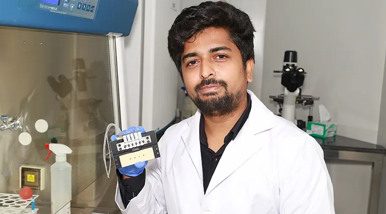 Ikram Khan in the lab holding the ISMO microfluidic chip